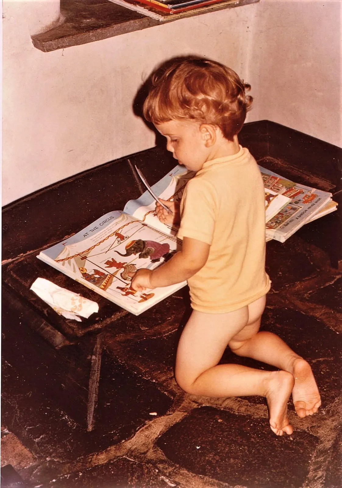 Rob as a small child, kneeling alone on a stone floor with his books