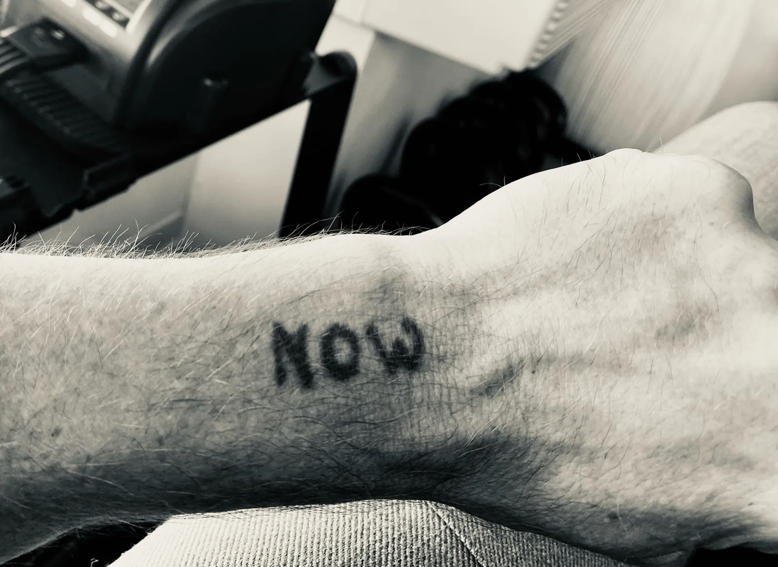 The word NOW tattooed on Rob Scott's forearm